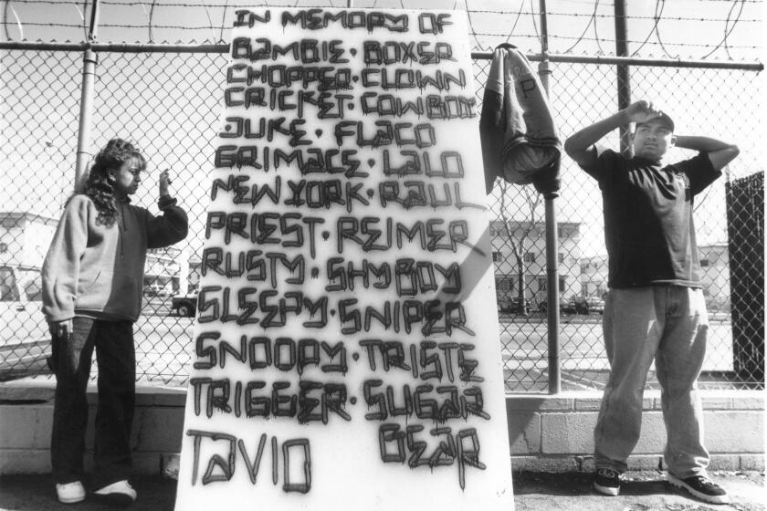 Artists Erica Parra and Joe Diaz in 1994 with a segment of a wall commemorating the deaths of gang members during the previous six years around Boyle Heights’ Pico-Aliso housing projects.