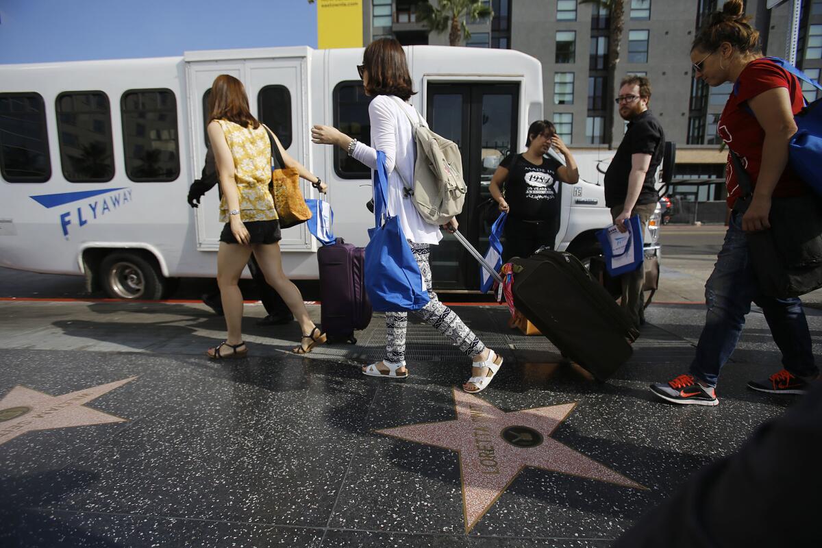 Passengers board the LAX FlyAway Bus on Hollywood Boulevard. The bus service between LAX and Santa Monica stopped operating Monday.