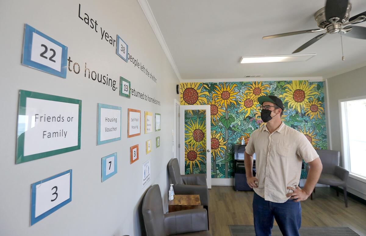 Manager Mike Fotion shows a wall with numbers that reflect housing placement results in the community room.