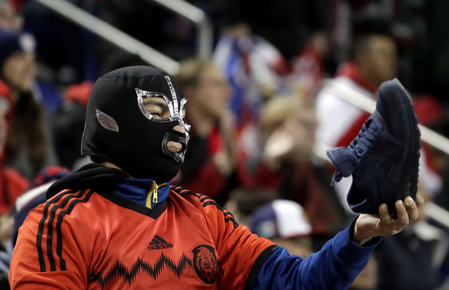 A spectator offers his shoe to New York Red Bulls forward Bradley Wright-Phillips, who lost his boot while competing against Guadalajara during the first half of the second leg of a CONCACAF Champions League soccer semfifinal Tuesday, April 10, 2018, in Harrison, N.J. The teams tied 0-0 and Guadalajara advanced on aggregate. (AP Photo/Julio Cortez)