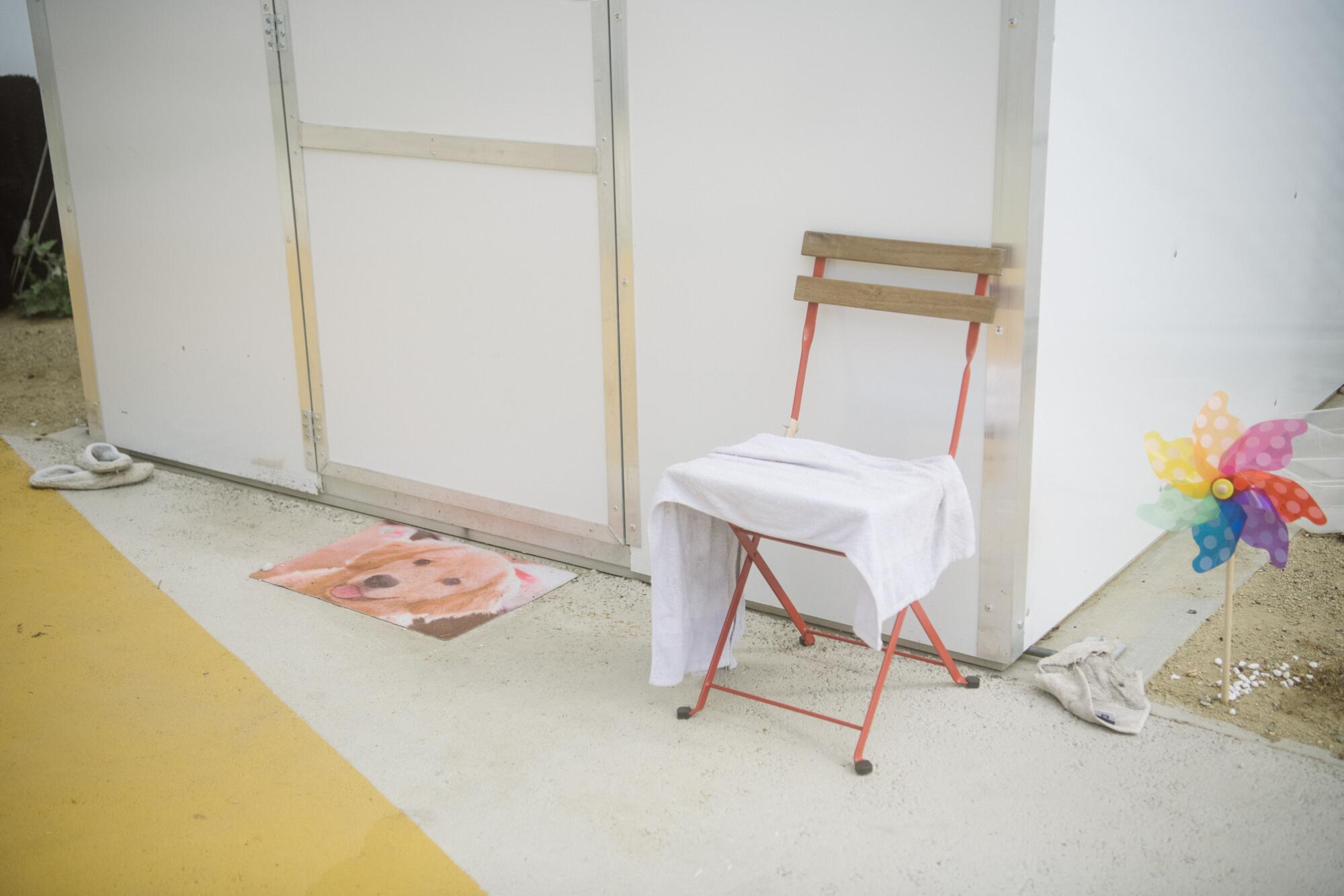 A  welcome mat with a dog's photo and a chair in front of a tiny home