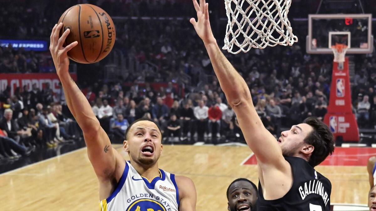 Warriors guard Stephen Curry, left, drives for a layup as Clippers forward Danilo Gallinari defends during the first half of a game on Jan. 18, 2019, in Los Angeles.