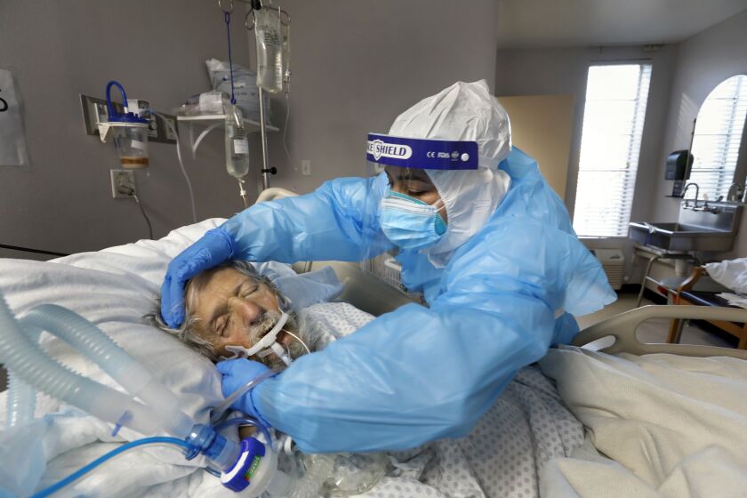 Houston, Texas-Dec. 9, 2020-Nurse Flor Trevino cares for one of her patients, Dr. George Thomas, age 75, of Beaumont, Texas on the Covid unit at Houston's United Memorial Medical Center. (Carolyn Cole / Los Angeles Times)