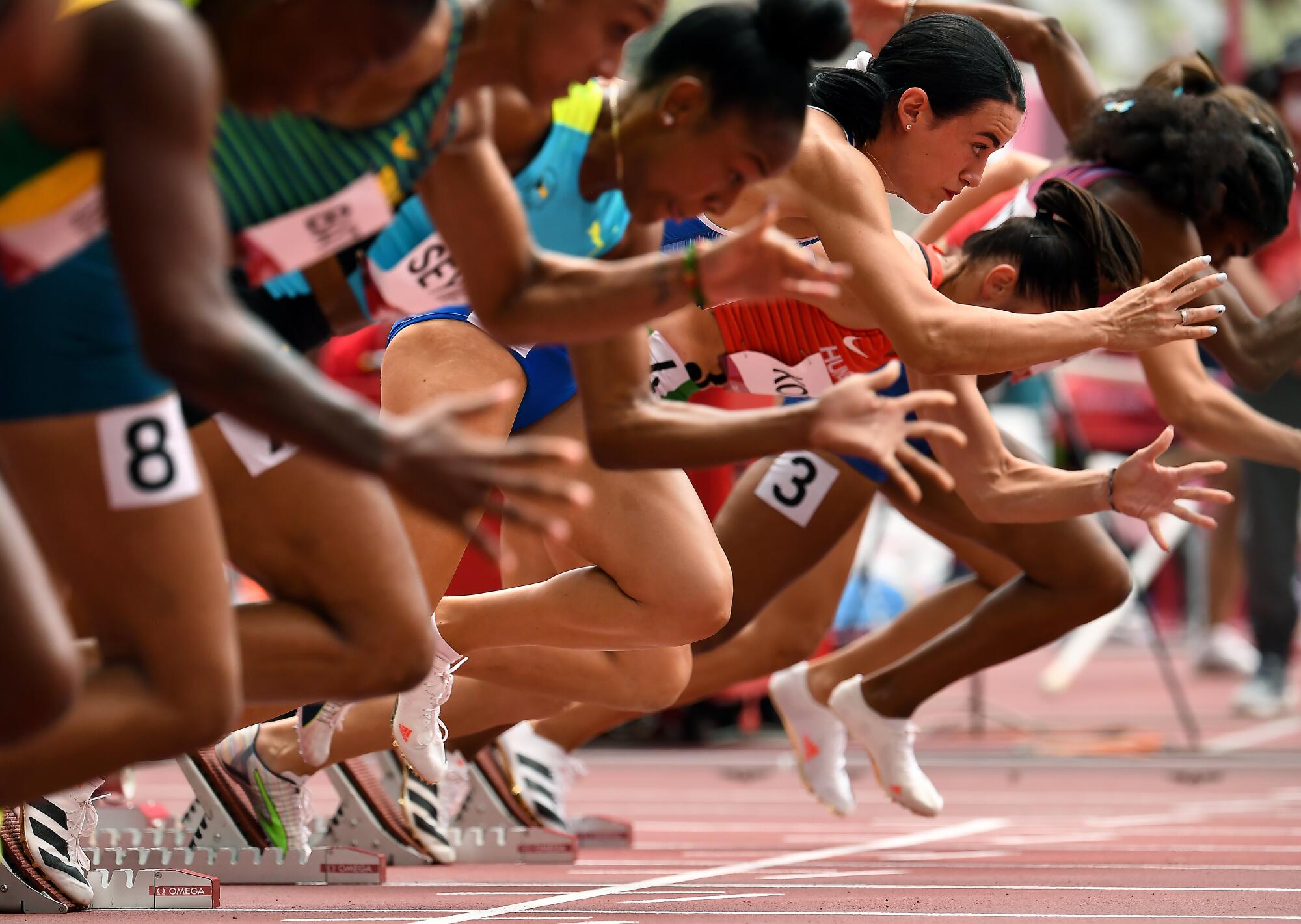 Women run the 100-meter hurdles at the Tokyo Olympics.