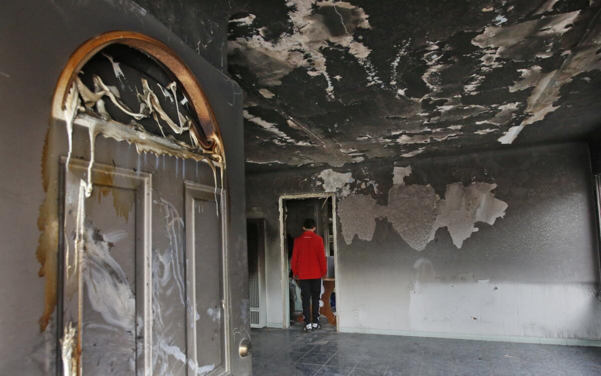 A relative walks through the home where a man died in a house fire in South Los Angeles on Saturday.