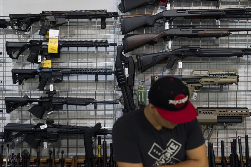 Sales associate Daniel Ramirez-Sosa looks at guns on display at Burbank Ammo & Guns in Burbank, Calif., Thursday, June 23, 2022. The Supreme Court has ruled that Americans have a right to carry firearms in public for self-defense, a major expansion of gun rights. The court struck down a New York gun law in a ruling expected to directly impact half a dozen other populous states. (AP Photo/Jae C. Hong)