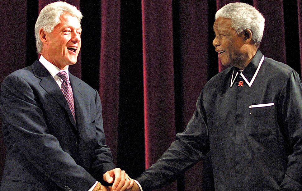 Former U.S. President Bill Clinton shakes hands with former South African President Nelson Mandela during the inaugural Nelson Mandela Lecture at the Johannesburg Civic Centre, on July 19, 2003. The lecture coincided with Mandela's 85th birthday.
