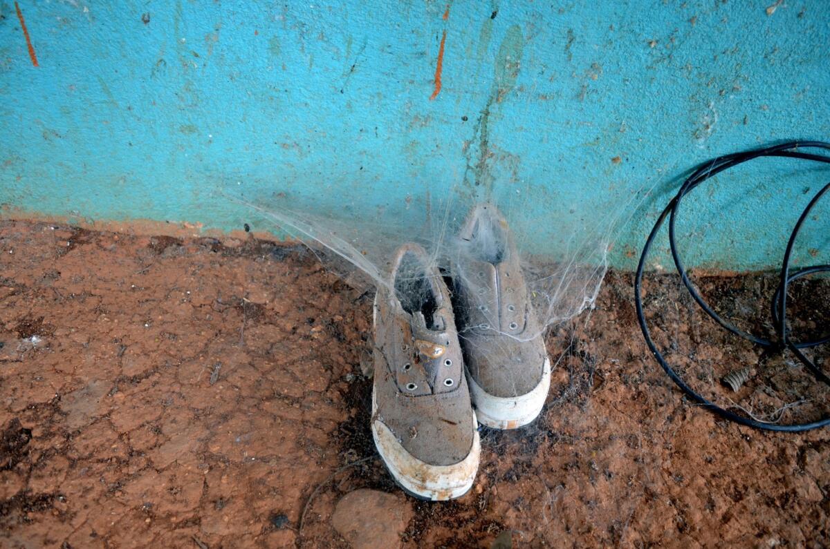 Cobwebs are taking over a pair of shoes left on a porch.