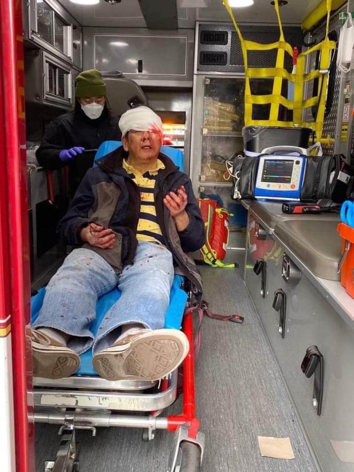 Danilo Yuchang, 59, sits in an ambulance with a white bandage around his head.