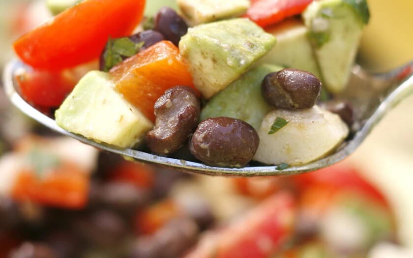 Close-up shot of a spoonful of beans, avocado and red pepper.