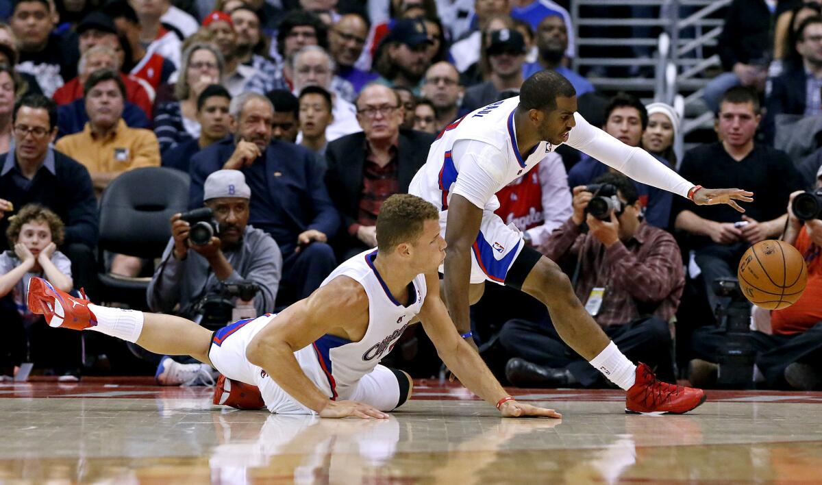Cllppers guard Chris Paul and teammate Blake Griffin scramble after a loose ball Tuesday against the Nuggets at Staples Center.