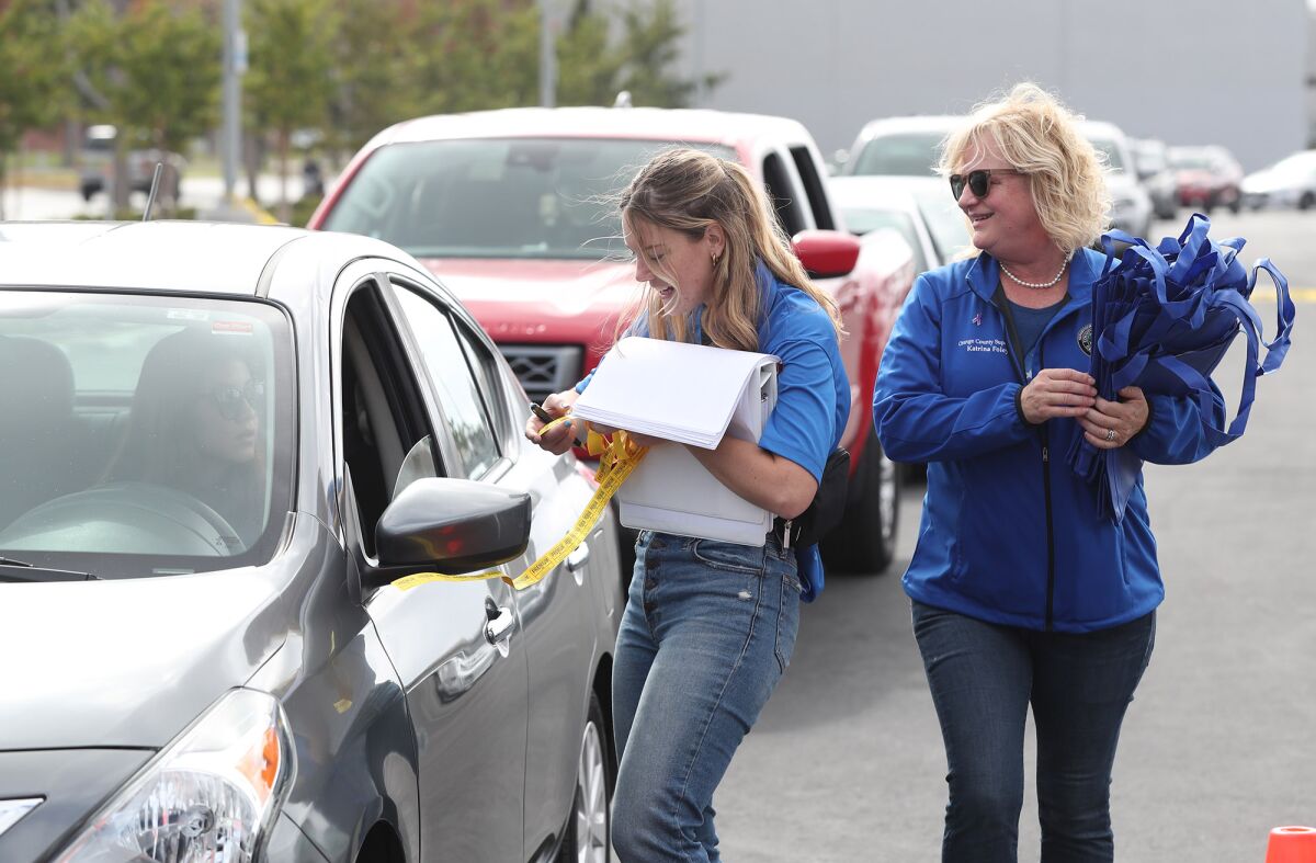 Supervisor Katrina Foley, right, and policy analyst Annie Mitchell greet motorists with $100 gas cards Tuesday at OCC.