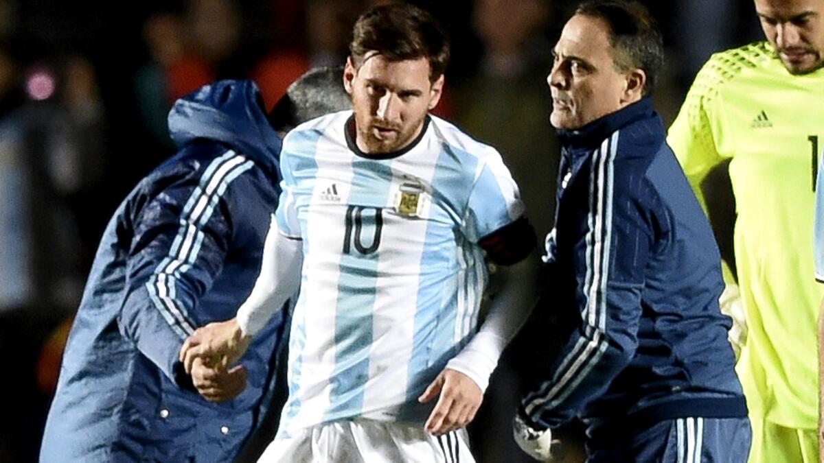 Trainers check on Argentina forward Lionel Messi, center, after he took a knee to the back during an exhibition game against Honduras on Friday.