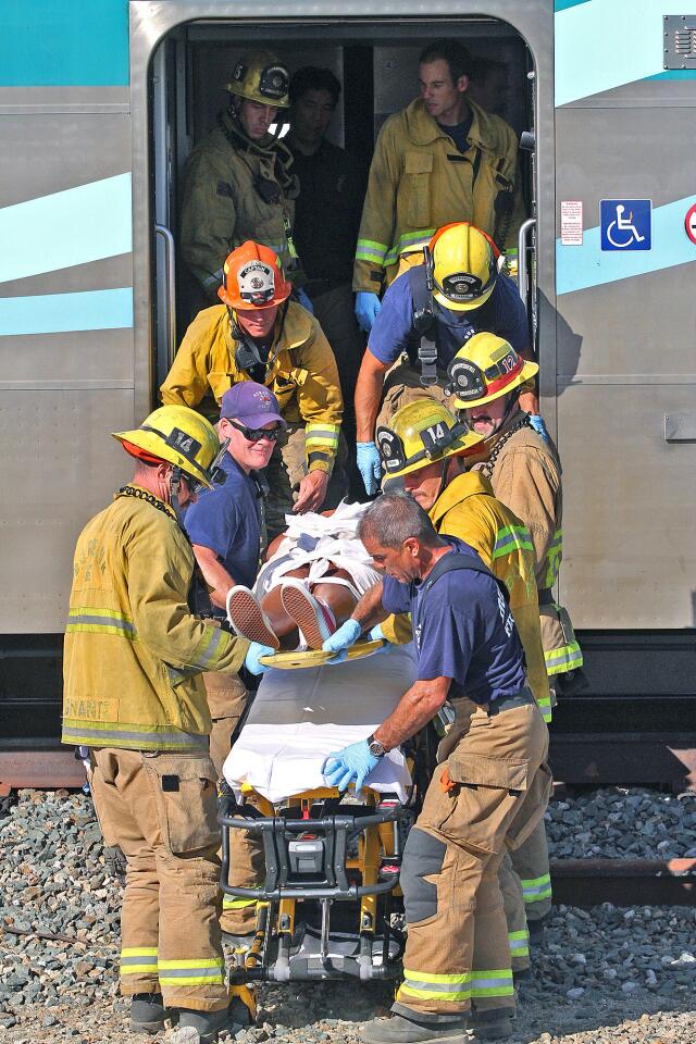 Burbank firefighters extract an injured Metrolink passenger to an awaiting ambulance south of the intersection of San Fernando and Buena Vista in Burbank on Monday, September 2, 2014. The southbound train struck a motorist allegedly driving around the downed crossing arms on Buena Vista totalling the vehicle and sending the driver to the hospital with critical injuries.