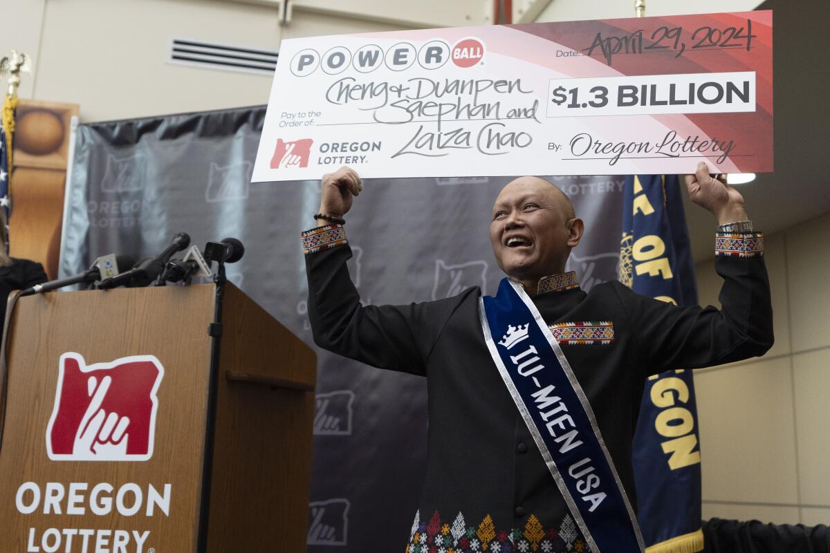 Cheng "Charlie" Saephan sostiene un cheque gigante por valor de 1.300 millones de dólares 