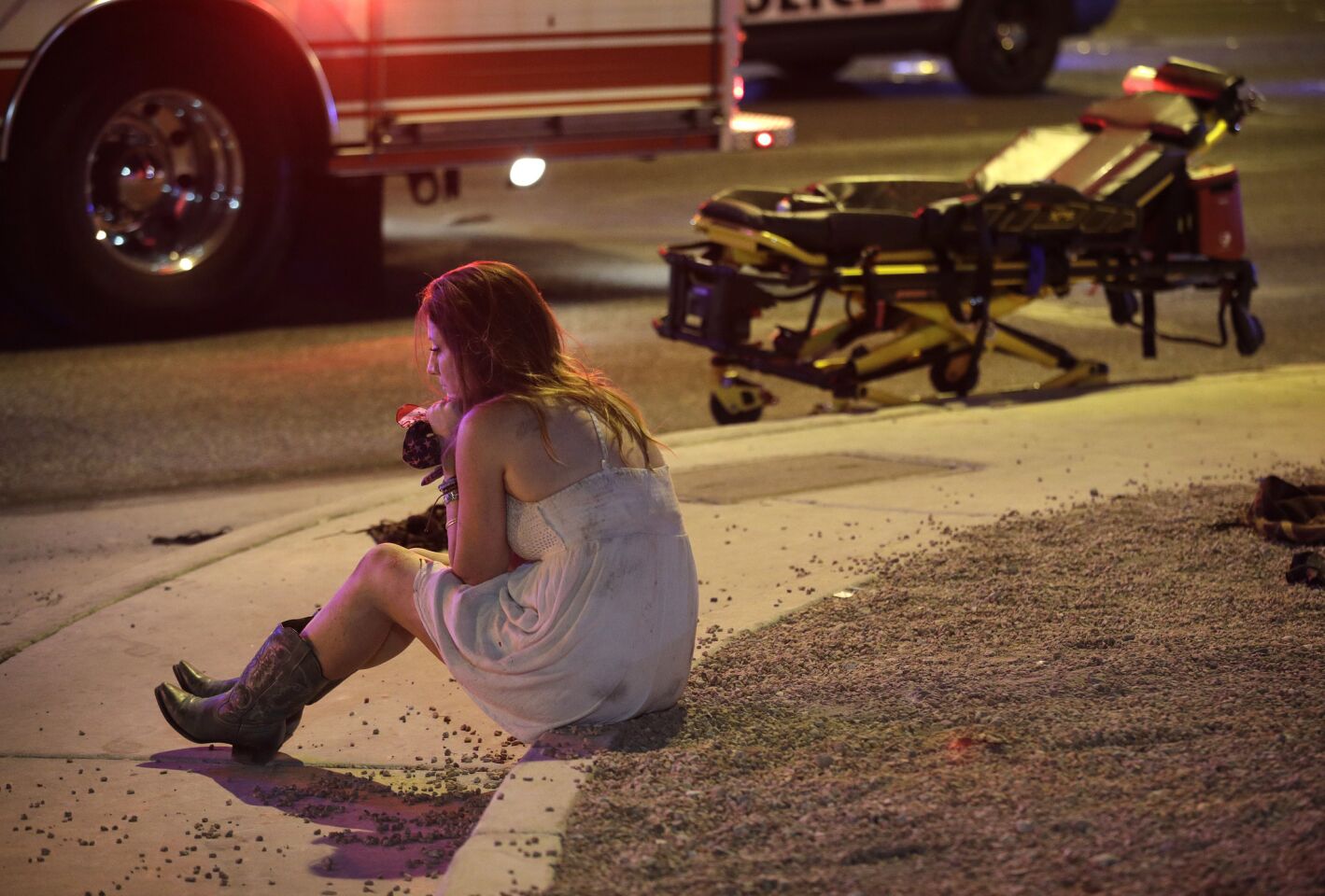 A woman sits on a curb at the scene of the shooting outside of the Route 91 Harvest country music festival along the Las Vegas Strip.
