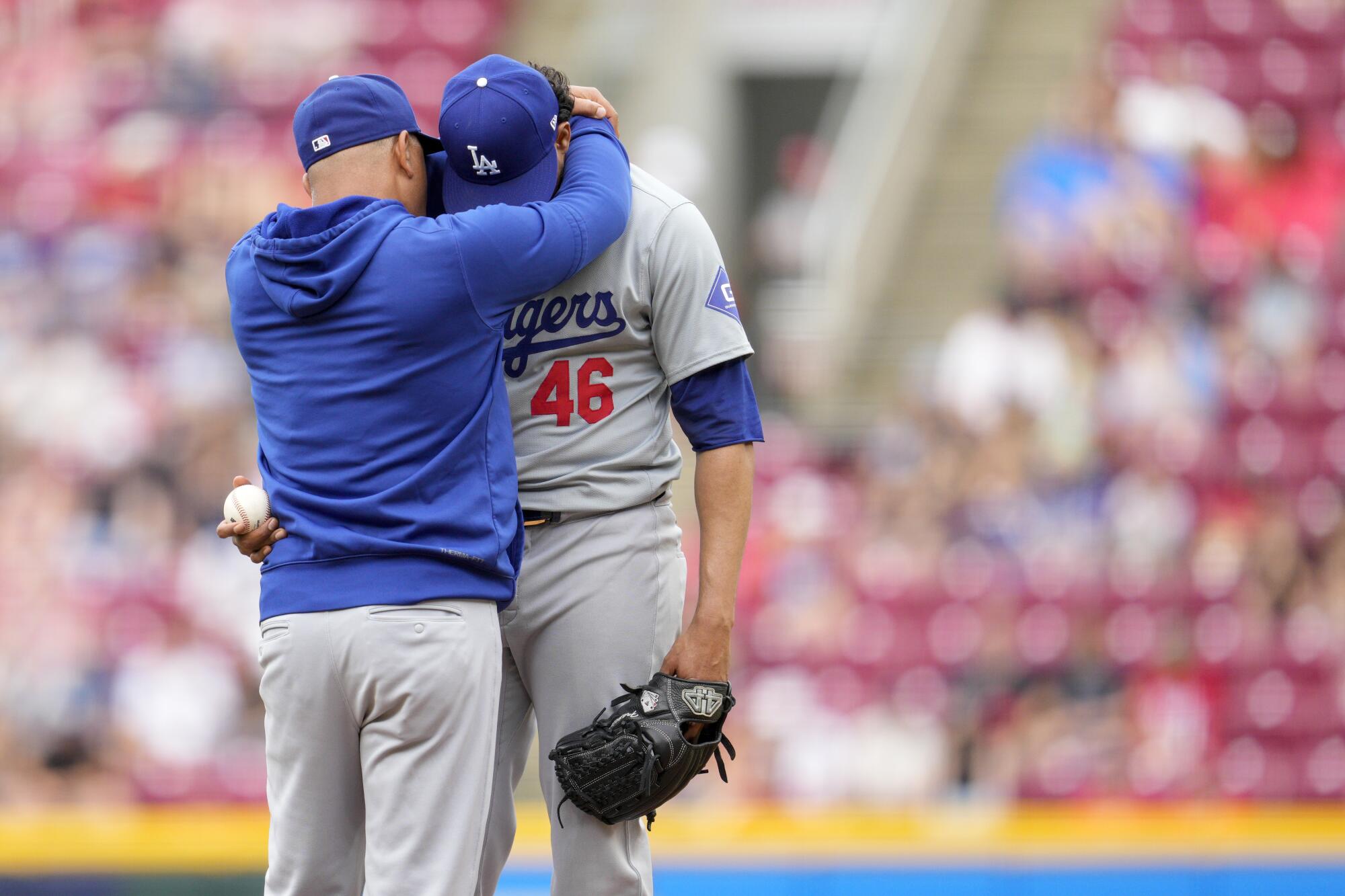 Dodgers pitcher Yohan Ramírez is embraced by manager Dave Roberts, left, during a game on May 26.