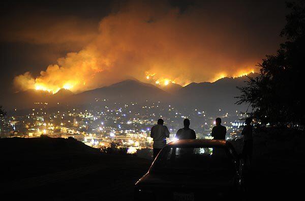 A group of young men watch the Station fire from a hill overlooking Tujunga on Monday night.
