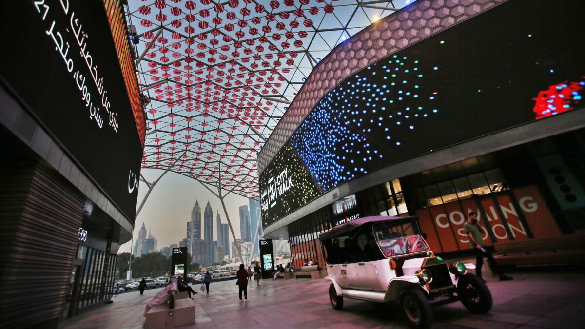 An electric classic-style car tours a shopping area in Dubai, United Arab Emirates.