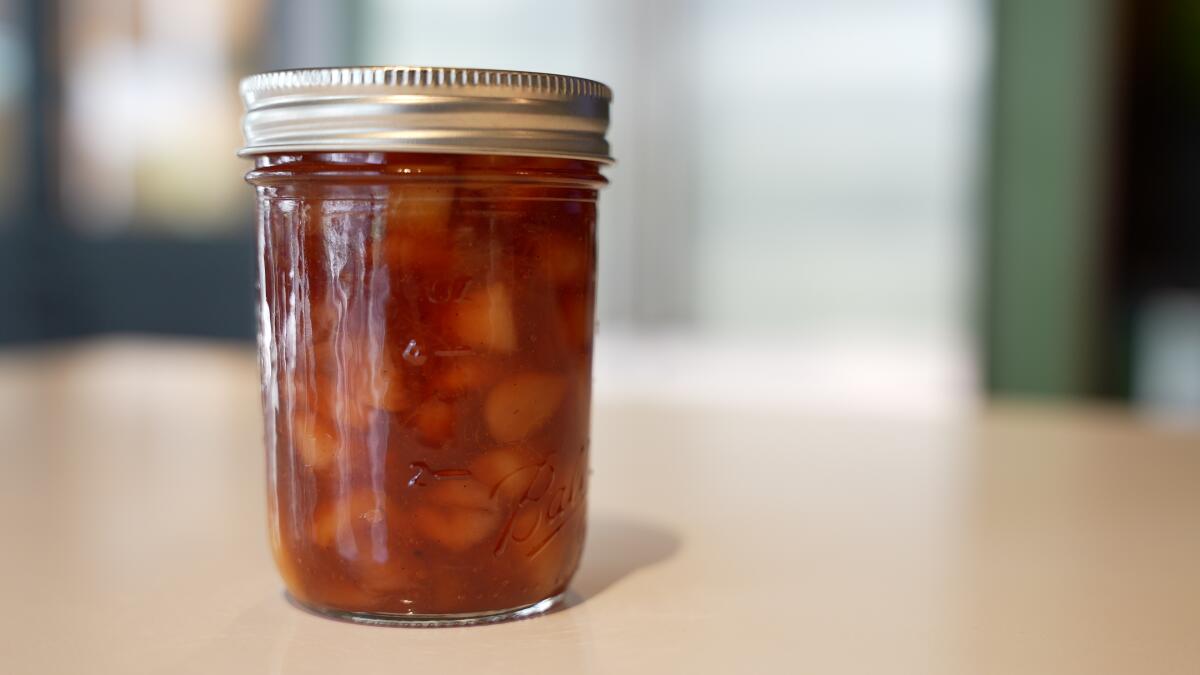 A jelly jar filled with peach jam with vanilla.