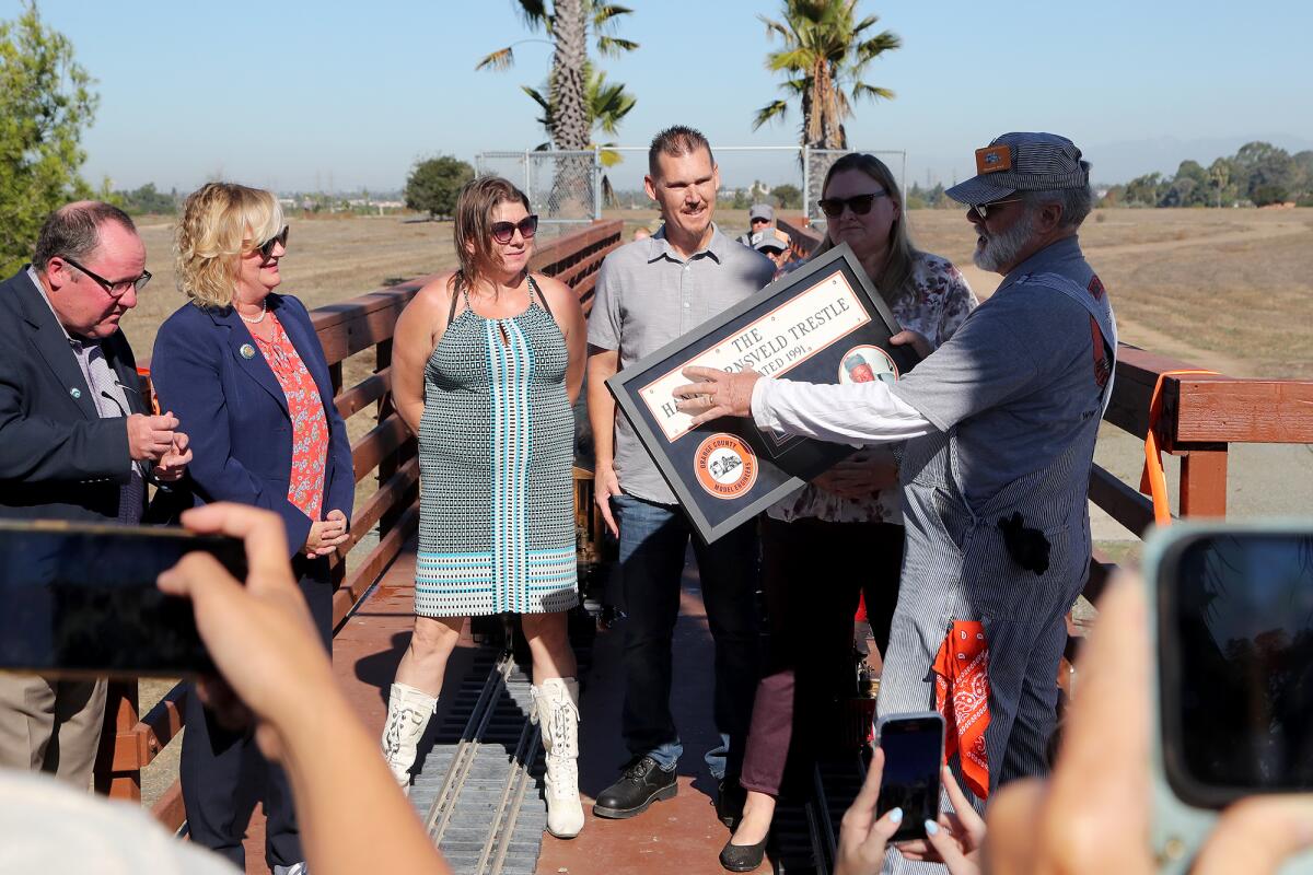 Dennis Neil, right, presents a plaque to Hank Hornsveld's grandchildren as Katrina Foley and John Stephens look on.