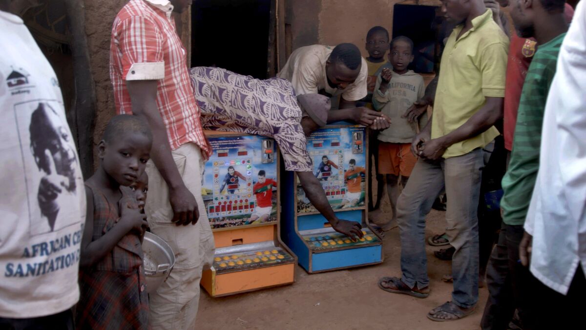 Villagers bring two gambling machines out from a hut in Zamashegu, in Ghana's Northern Region. (Noah Fowler / For The Times)