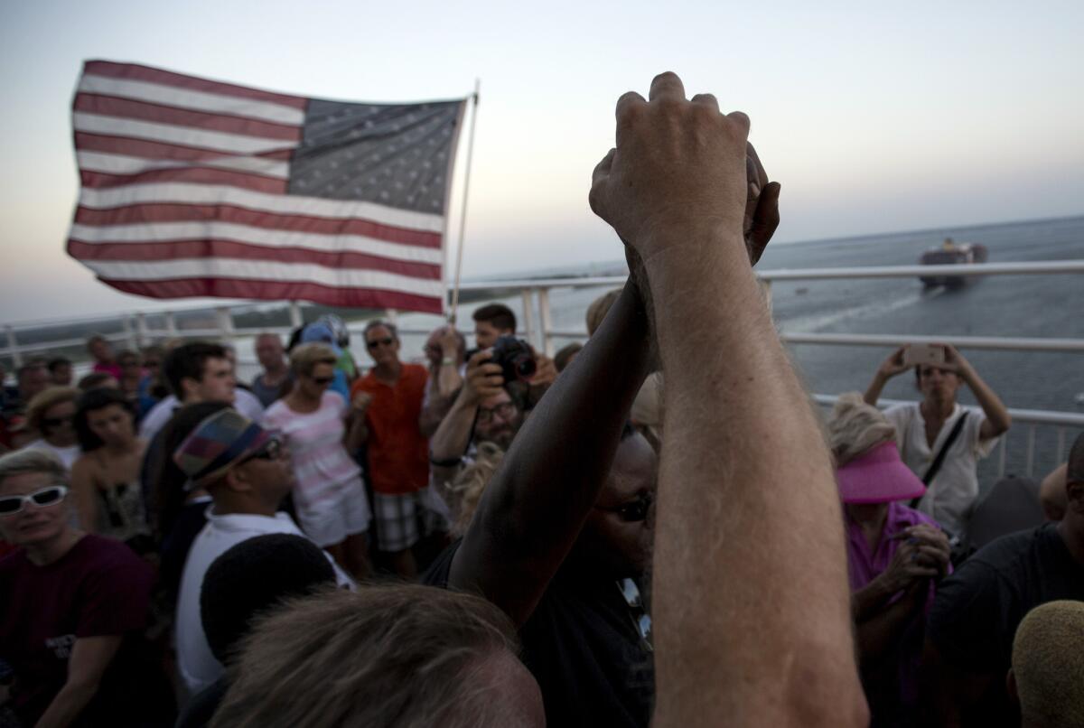 Gente alzando las manos en muestra de unidad mientras miles de manifestantes se reúnen en medio del principal puente de Charleston después de que nueve parroquianos negros fueran asesinados cuando estudiaban la Biblia, el domingo 21 de junio de 2015, en Charleston, Carolina del Sur.