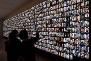Visitors look at photos of Israeli people who were killed during Hamas militants attack on Oct. 7 and those who died during the Israel-Hamas war in the Gaza Strip, displayed on a giant screen at the National Library in Jerusalem, Israel, Sunday, Jan. 28, 2024. (AP Photo/Leo Correa)