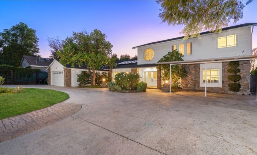 Gated and landscaped, the nearly half-acre property holds a two-story home and a swimming pool out back.