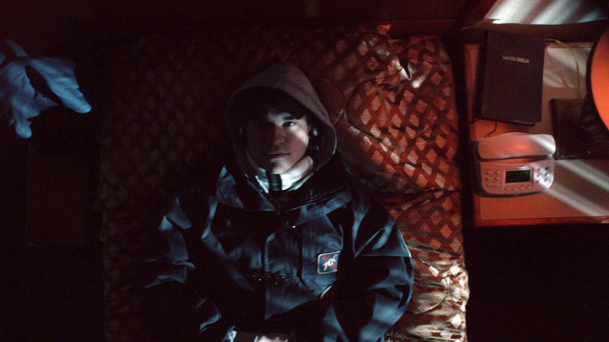 A man in a hooded jacket lies on a bed.
