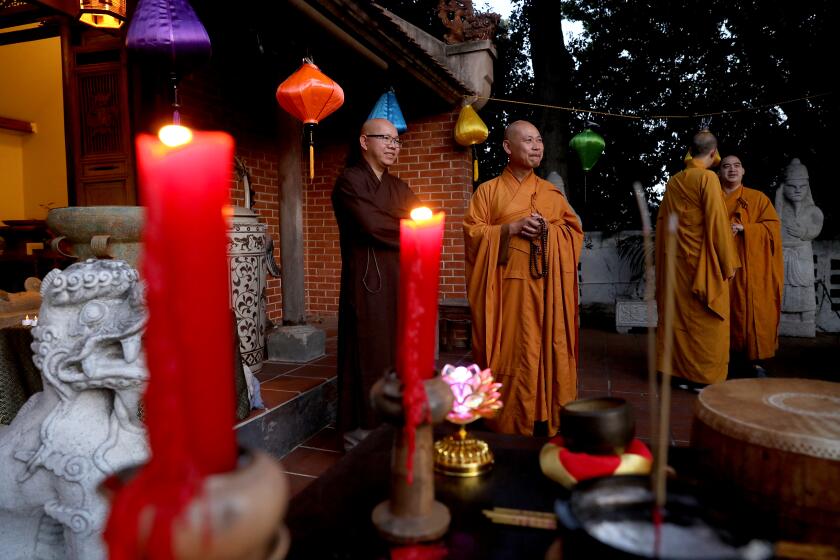 SANTA ANA, CA - MAY 17: Buddhist monks Quang Hieu, far left, of the Bat Nha Temple in Santa Ana, and Thich Vien Huy, center, of the Dieu Ngu Temple in Westminster, before the start of a candlelight vigil at the Viet Heritage House & Garden on Tuesday, May 17, 2022 in Santa Ana, CA. Orange County faith leaders -- including Buddhist monks and Catholic priests -- will hold a candlelight vigil to mark the 1 million lives lost in the coronavirus pandemic, as well as the victims of the shootings in Buffalo and Laguna Woods. (Gary Coronado / Los Angeles Times)