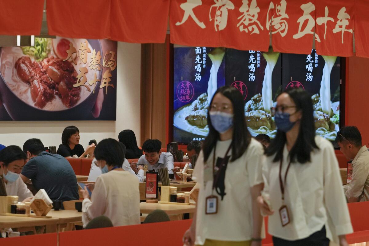 Women wearing face masks walk by a reopened restaurant in a shopping mall as new COVID-19 cases drop in Beijing Monday, June 6, 2022. (AP Photo/Andy Wong)