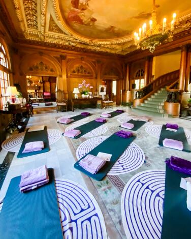 Blue mats with purple towels laid out in an ornate room with labyrinth designs on the floor
