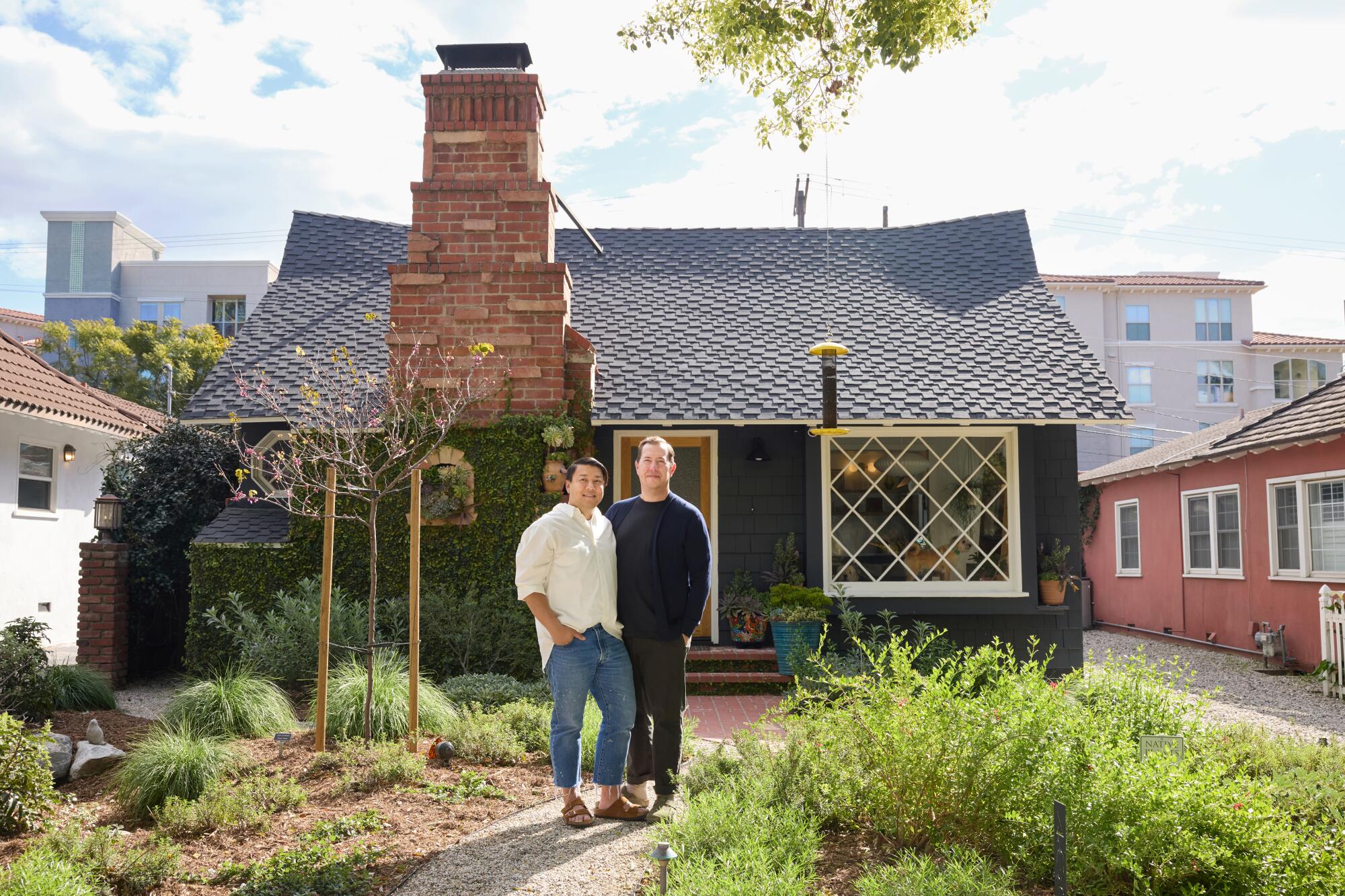 Two men standing close together in the front yard of their Storybook cottage.