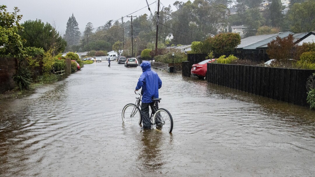 A person bikes through floodwaters