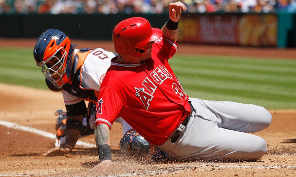 Angels outfielder Josh Hamilton slides safely past Houston Astros catcher Carlos Corporan during the first inning of the Angels' 9-1 win Monday afternoon.