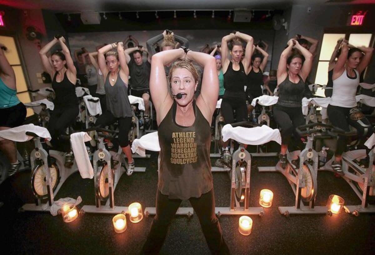 Instructor Janet Fitzgerald leads a class at SoulCycle, an indoor cycling studio based in New York. Arm weights are part of the class.