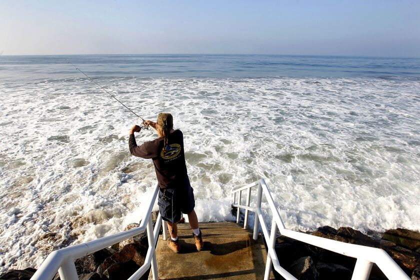  Joe Dombroski of Canoga Park fishes off public access stairs during high tide at Broad Beach in Malibu
