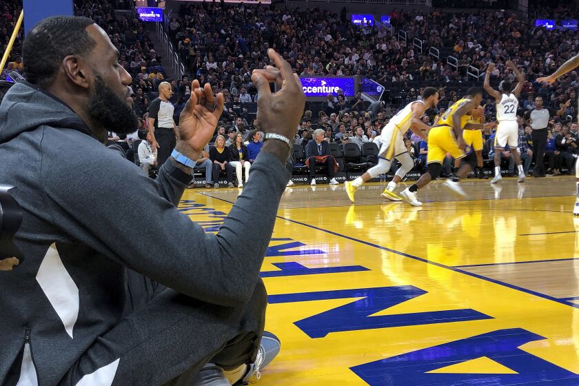 Lakers forward LeBron James sits along the baseline, appearing to meditate, during the exhibition game against the Warriors on Friday.