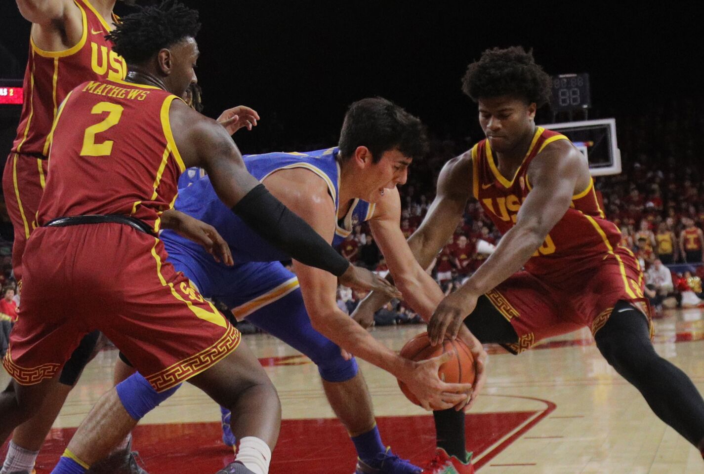 USC guards Jonah Mathews (2) and Ethan Anderson (20) try to rip the ball away from UCLA guard Jaime Jaquez Jr. during the first half of the Trojans' 54-52 victory over the Bruins at Galen Center on March 7, 2020.