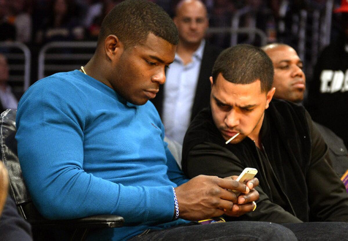 Dodgers outfielder Yasiel Puig checks his phone while attending a Lakers-Pacers game at Staples Center last week.