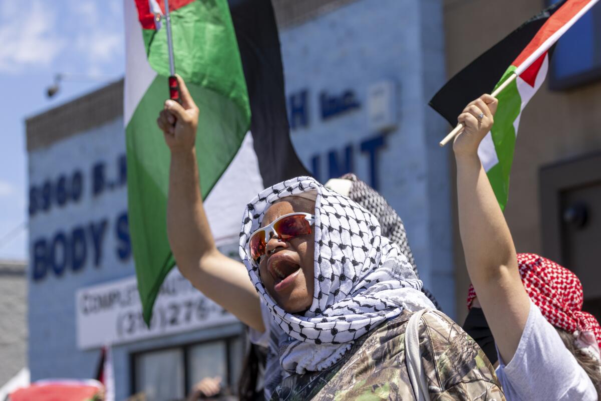 Protesters in kaffiyehs wave Palestinian flags.