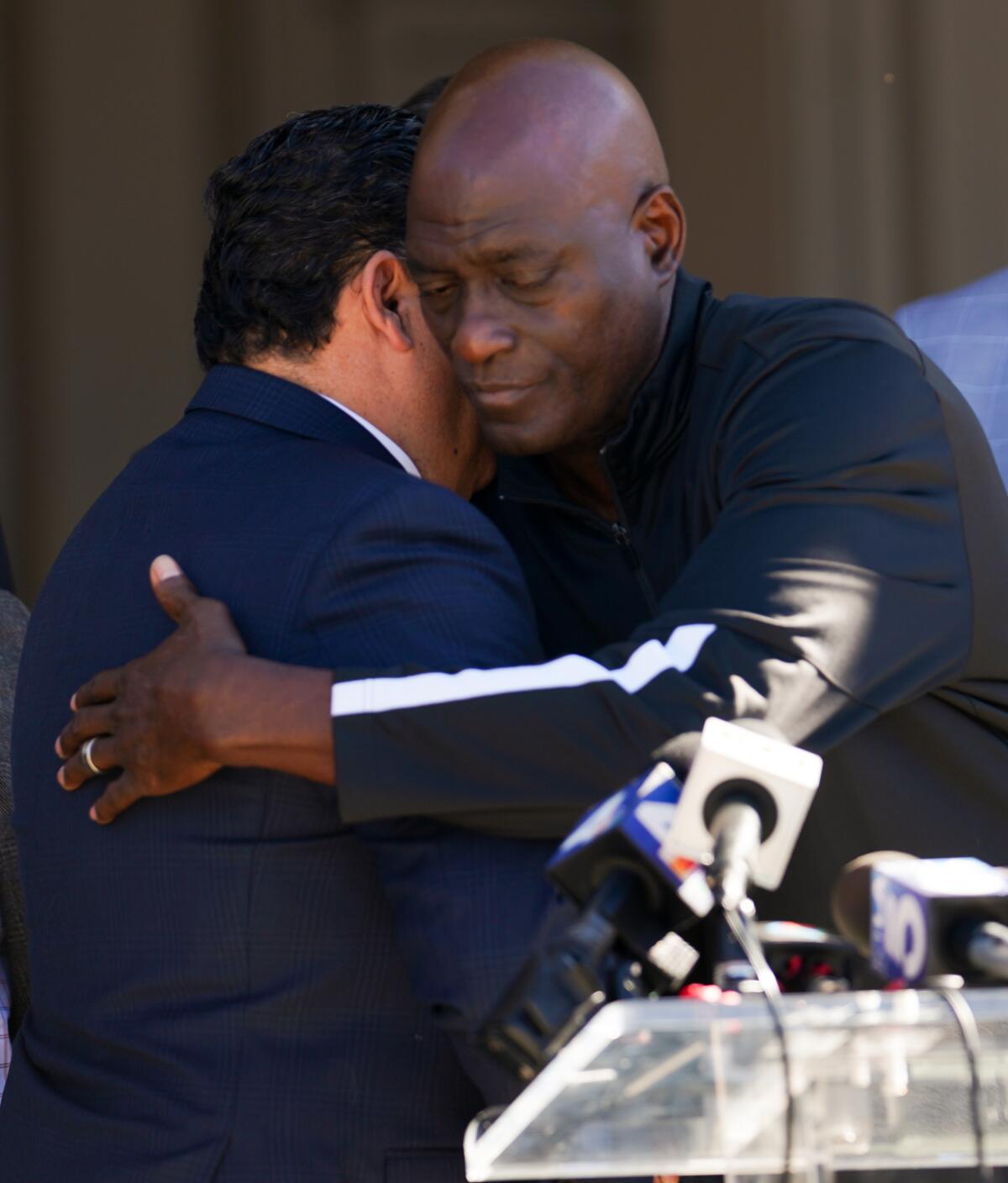 Michael Cooper, right, hugs Pasadena Mayor Victor M. Gordo