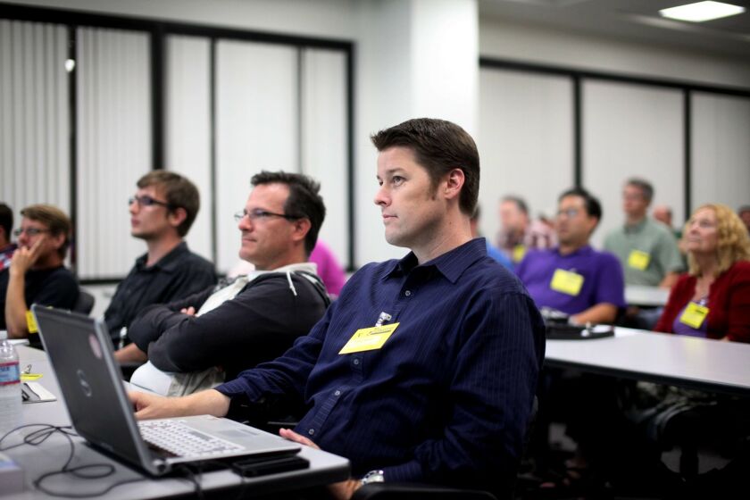 Local technology workers, including Phelan Riessan,Middle, listen to web developer Gina Trapini(not pictured) speak during a meeting at Qualcomm in Sorrento Valley on Tuesday, Aug. 9, 2011.