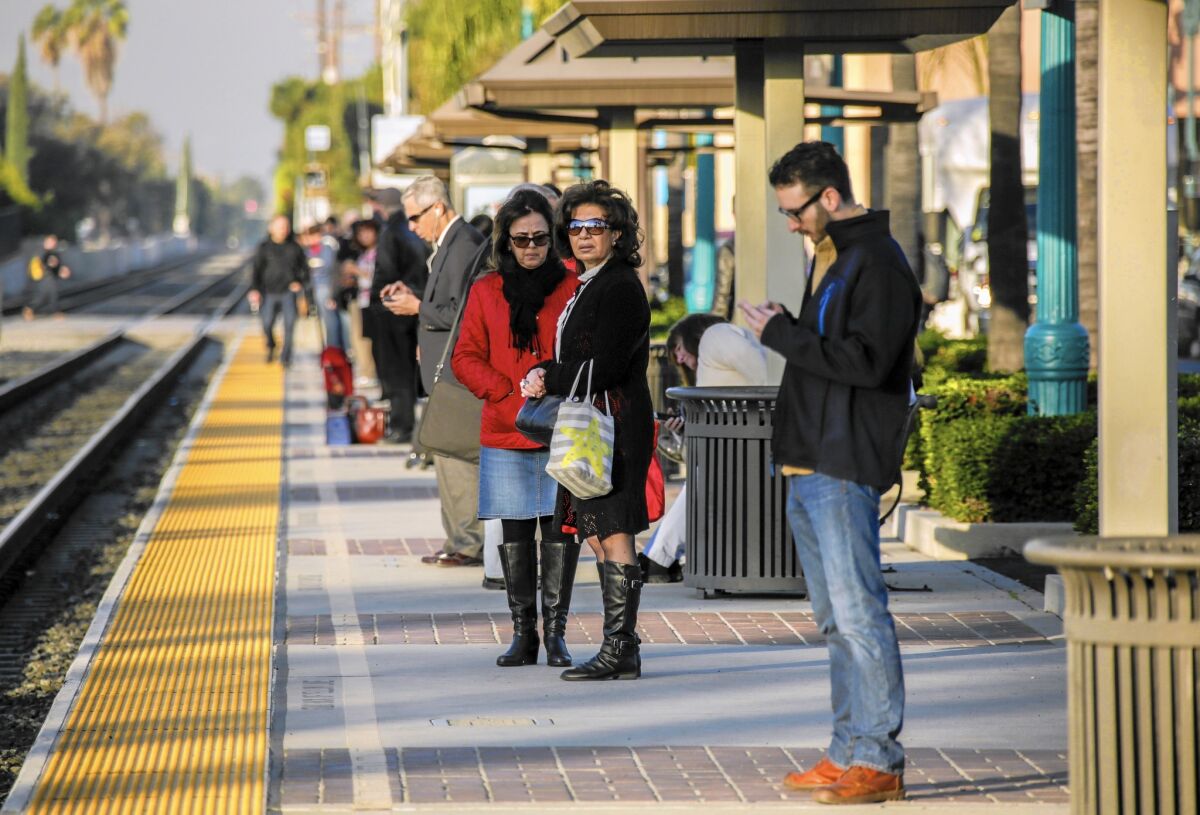 Commuters wait for a train at Metrolink's Covina station last week.