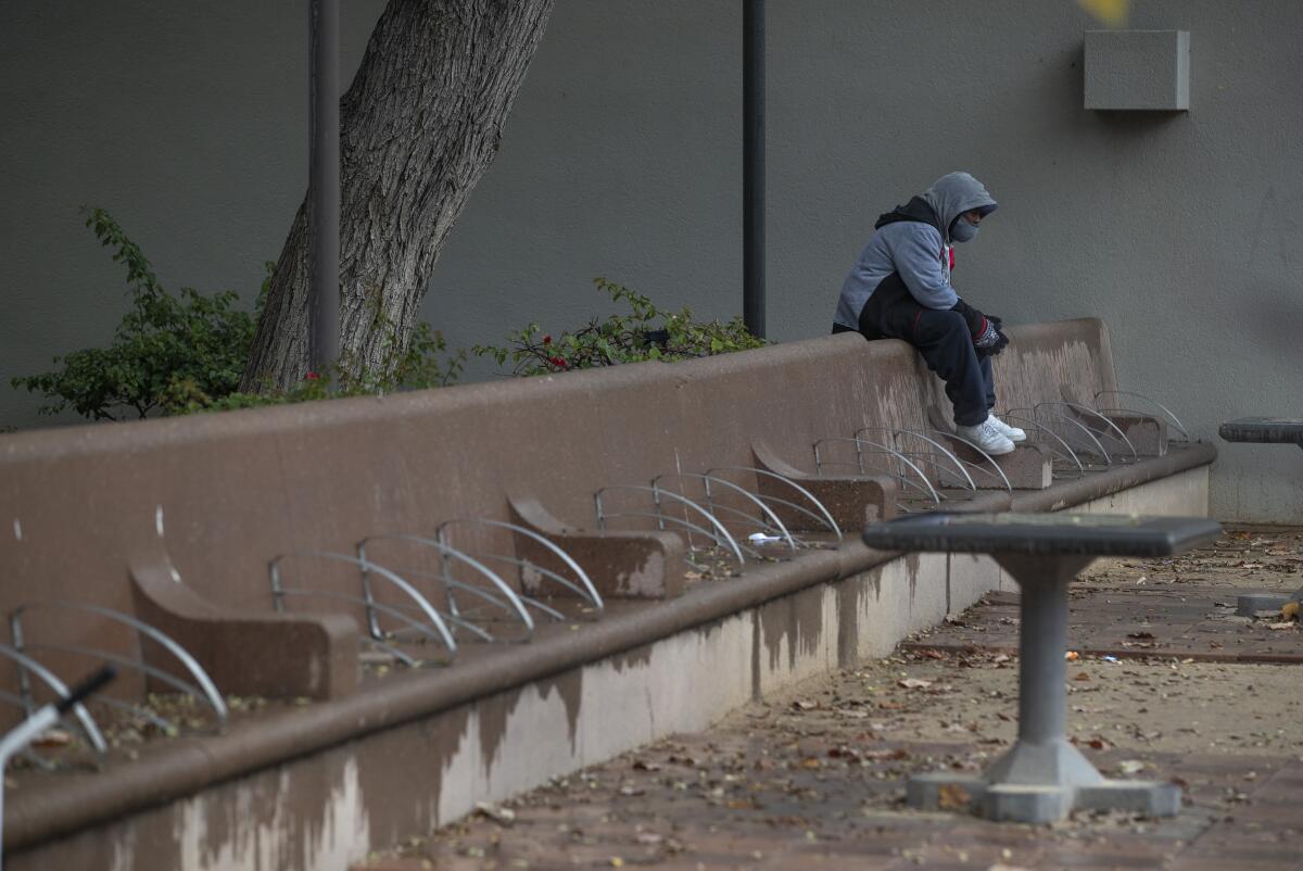 A man sits alone during a visit to Pershing Square in downtown Los Angeles on a rainy afternoon. 