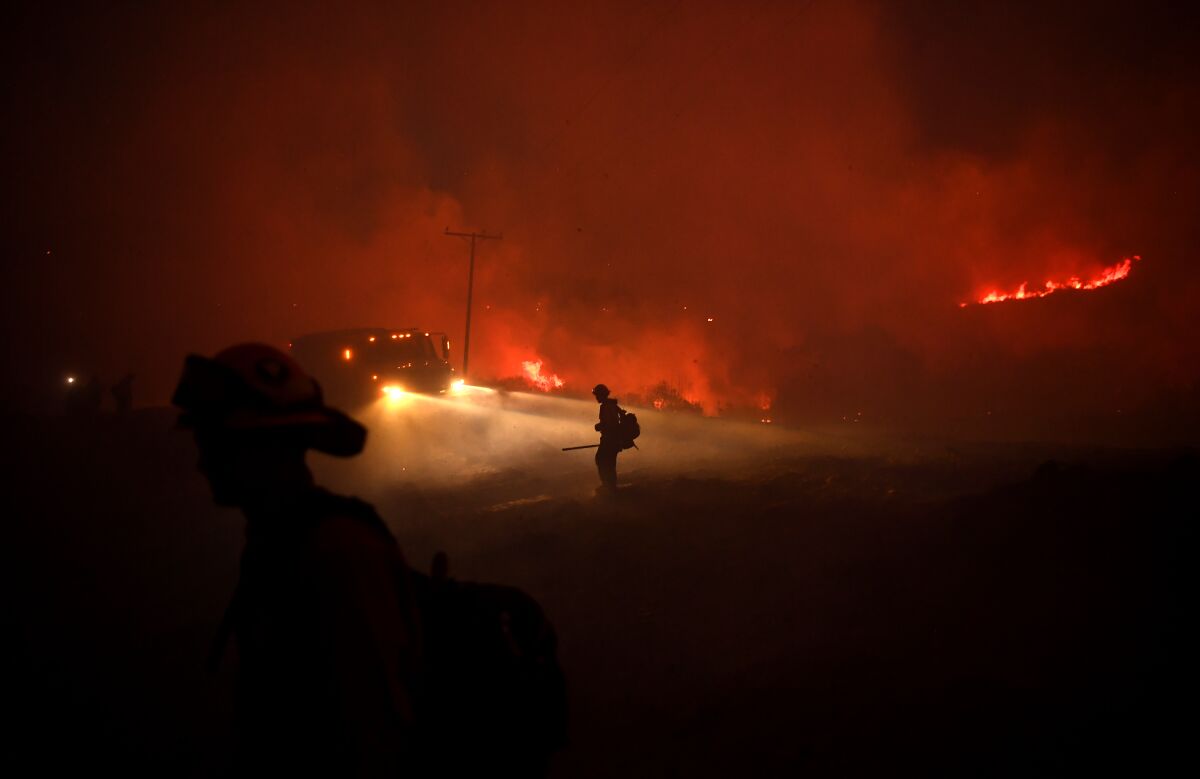 Firefighters work to put out embers from the El Dorado Fire in Yucaipa Monday.