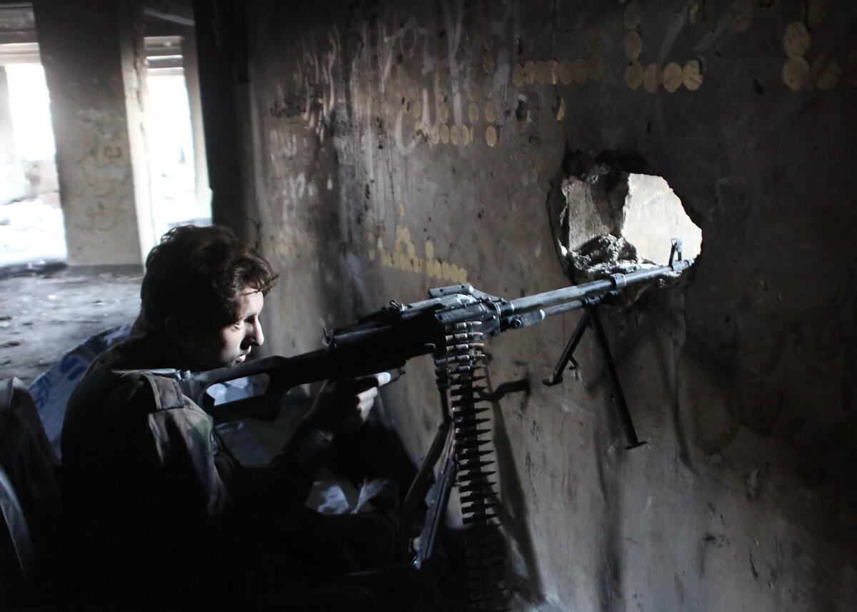 A member of Syria's pro-government forces peers through lookout in Aleppo.