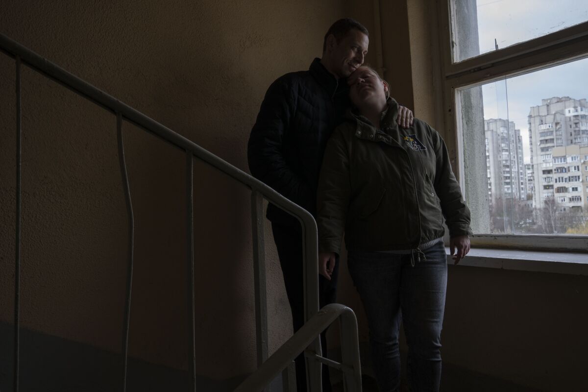 Iryna and Volodymyr, internally displaced from Irpin, lean on each other, on the stairwell near an apartment they took refuge in with four other adults from Irpin, in Lviv, western Ukraine, Sunday, April 3, 2022. Iryna and her husband Volodymyr were trapped for days between Ukrainian and Russian forces and quickly learned to distinguish between incoming and outgoing fire. They took shelter in a basement and whenever the shelling eased, they climbed out to shout to their neighbors to see if they were still alive. (AP Photo/Nariman El-Mofty)