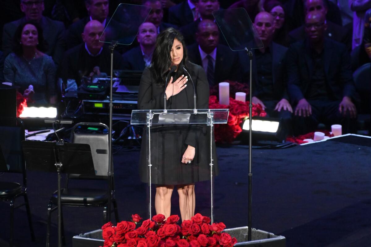 Vanessa Bryant speaks at a lectern surrounded by roses.